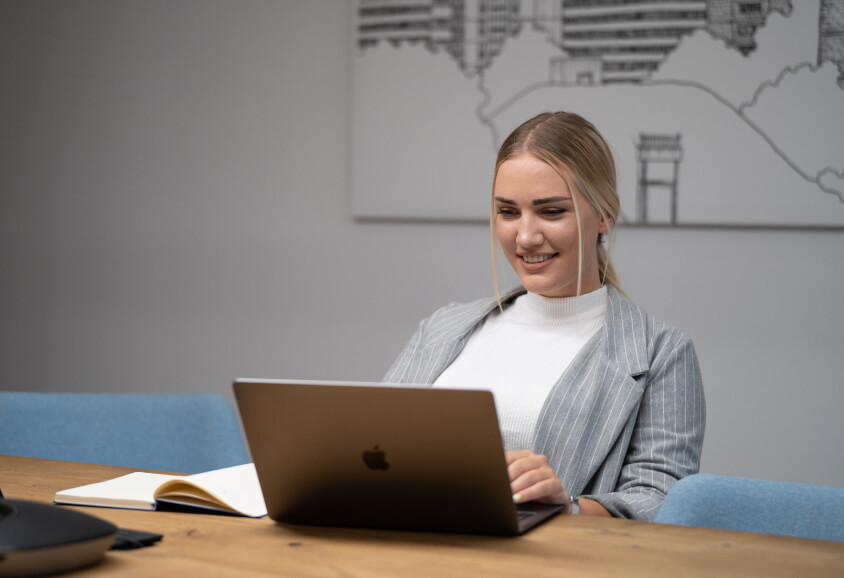 blonde girl in a blaxer, working on a Mac